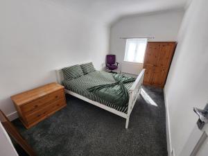a bedroom with a bed and a dresser and a window at The Moonflower in Grays Thurrock