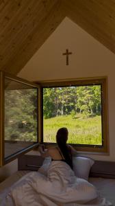 a woman laying in bed looking out of a window at Dolina nad Drawa in Przeborowo