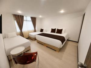 a hotel room with two beds and a chair at Zentio Hotel in Bogotá