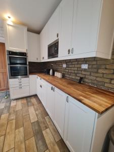 a kitchen with white cabinets and a wooden counter top at The Carnation in Grays Thurrock