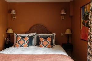 a bedroom with a bed with orange walls and pillows at The Great Decoy in Hurstbourne Tarrant