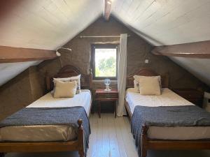 two beds in a attic room with a window at Casa do Avô Grande in Esposende