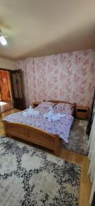 a bedroom with a bed in a room with pink wallpaper at Casa Răzvan in Arieşeni +4 photos