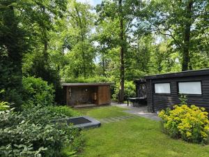 a black cabin in the middle of a yard at Scandinavian Forest Cabin in Twente in Markelo +5 photos