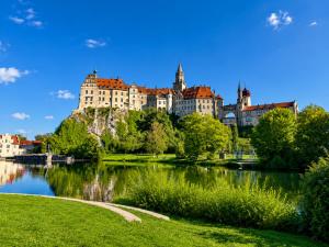 a large castle on a hill next to a river at Panoramablick mit Premium-Wanderwegen vor der Haustür in Albstadt