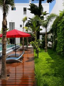 a deck with a red umbrella and chairs and a pool at Riad Maison de ville piscine privée in El Jadida