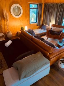 a living room with a large brown leather couch at Fiery Peak Eco-Retreat with Stargazing & Hot tub in Geraldine