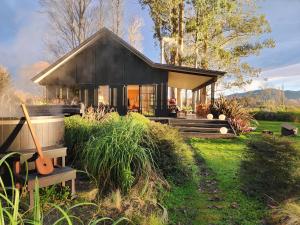 a small black house with a porch and a yard at Fiery Peak Eco-Retreat with Stargazing & Hot tub in Geraldine