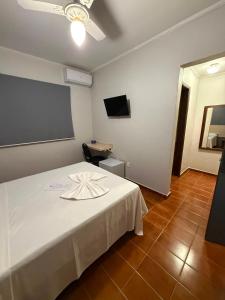 a bedroom with a white bed with a table and a ceiling fan at Bravo City Hotel Campinas in Campinas