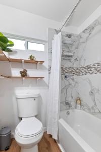 a bathroom with a toilet and a bath tub at Le Petite Willow - Guesthouse in Modesto
