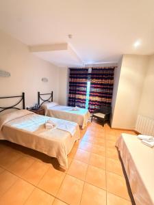 a room with two beds and a window at Hostal Restaurante Portell in Portell de Morella