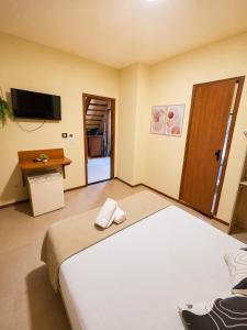 a bedroom with a large bed and a television at Pousada La Cabana in Itacaré