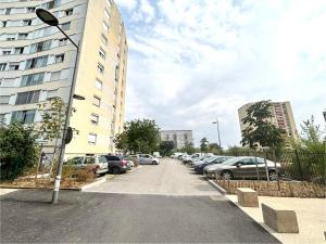 a parking lot with cars parked next to a tall building at Bricks Pérignon - Tram, lit Queen size & air fryer in Chenôve