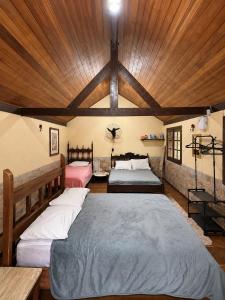 a bedroom with two beds and a wooden ceiling at Chalé Sonho Meu Penedo in Itatiaia