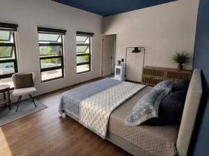 a bedroom with a bed and a chair and windows at Guesthouse AngaLampoe in Lelydorp