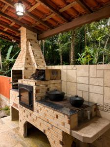 an outdoor kitchen with two pots on a brick oven at Chalé Sonho Meu Penedo in Itatiaia
