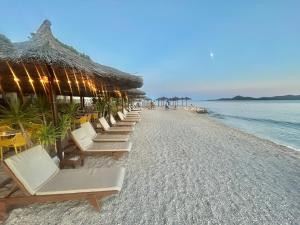 a row of chairs and umbrellas on a beach at Mobile Home David-Camp Soline in Biograd na Moru