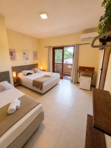 a hotel room with two beds and a balcony at Pousada La Cabana in Itacaré