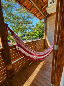 a hammock on a wooden porch with a window at Pousada La Cabana in Itacaré
