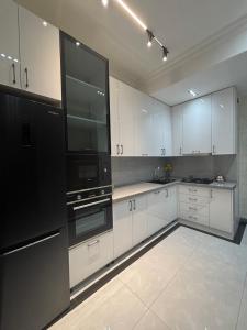 a large kitchen with white cabinets and black appliances at Huzur tapacaginiz ev in Sumqayıt