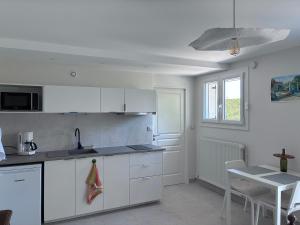 a white kitchen with a sink and a table at La Petite Provence in Arbois