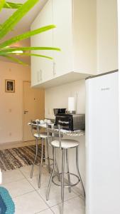 a kitchen with white cabinets and bar stools at Aconchego e praticidade no centro histórico in Itu