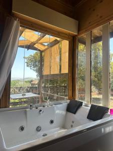 a bath tub in a room with a large window at Fashet alsalt in Al Salt