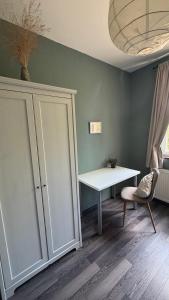 a room with a cabinet and a table and a chair at Rózsa Vendégház INGYENES PARKOLÁSSAL in Nagykovácsi