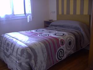 Una cama en un dormitorio con una manta. en Pensión Gema, en Irún
