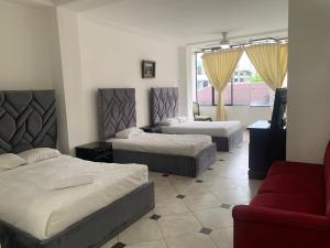 a bedroom with two beds and a red couch at Christian Palace in Tena