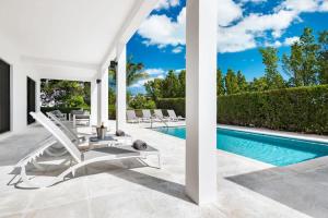 a pool with lounge chairs next to a swimming pool at Bora 4 BR Villa in Long Bay Hills