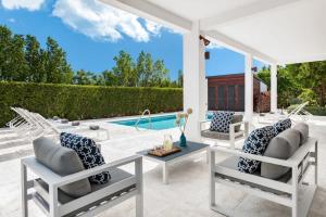 a patio with white chairs and a pool at Bora 4 BR Villa in Long Bay Hills