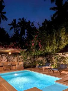a swimming pool in a yard with two benches and flowers at Casa del Mar Diani in Diani Beach