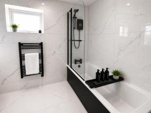 a white bathroom with a tub and a shower at 3 Bed House , Bootle , Discounts , Long Stays , Contractors , Families , Relocation Stays in Liverpool +6 photos