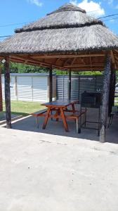 a picnic table in a pavilion with a straw roof at MALU casa quinta in Rafaela