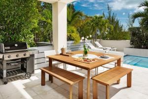 a patio with a wooden table and a grill at Second Wind Villa in Long Bay Hills