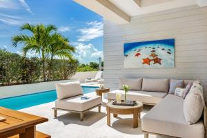 a living room with white furniture and a swimming pool at Second Wind Villa in Long Bay Hills