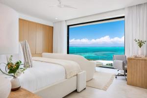 a white bedroom with a view of the ocean at Beachwood Villa in Turtle Cove