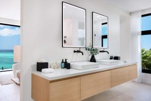 a bathroom with two sinks and two mirrors at Beachwood Villa in Turtle Cove