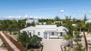 a white house on the beach with palm trees at Villa Seadream - Upper East Side Enclave #16 in Long Bay Hills
