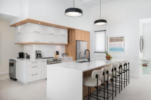 a kitchen with white cabinets and a bar with stools at Villa Seadream - Upper East Side Enclave #16 in Long Bay Hills