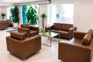 a waiting room with brown leather chairs and a table at Alko Select in Cali