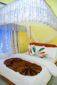 a bedroom with a canopy bed with white sheets and pillows at JOSEPHINA LODGE Dodoma in Dodoma