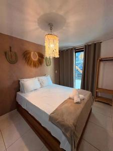 a bedroom with a large bed with a chandelier at Casa Macao Pipa in Pipa