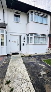 a white house with a white door and a driveway at Chadwell Heath Rooms in Goodmayes
