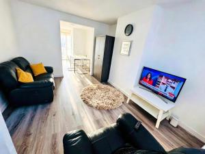 a living room with a couch and a flat screen tv at Chadwell Heath Rooms in Goodmayes