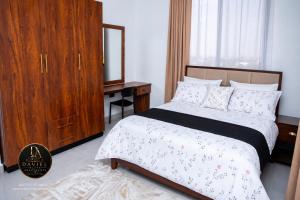 a bedroom with a bed with a dresser and a mirror at Daviel Elite Apartments in Dodoma