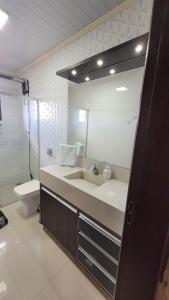 a bathroom with a sink and a toilet and a mirror at Próximo aSerra do Rio do Rastro in Lauro Müller +29 photos
