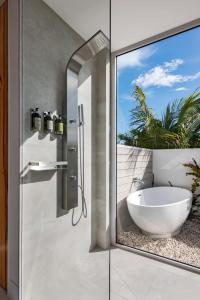 a bathroom with a glass shower door with a white tub at Ocean Dream Studio Blue - Ocean View in Long Bay Hills