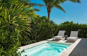 a swimming pool with two lounge chairs and a swimming poolvisor at Ocean Dream Studio Blue - Ocean View in Long Bay Hills